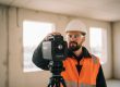 Techniker mit Faro Focus 3D-Laserscanner auf Wohnhaus-Rohbaustelle – rote Laserlinien zeigen den aktiven Scanvorgang
